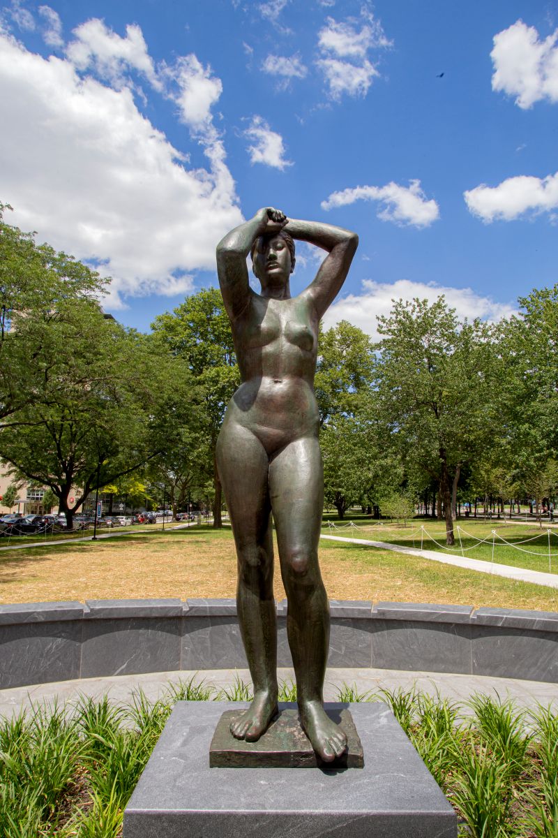 Bronze statue of a nude woman with hands raised